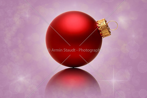 close up of a red christmas ball with purple star background