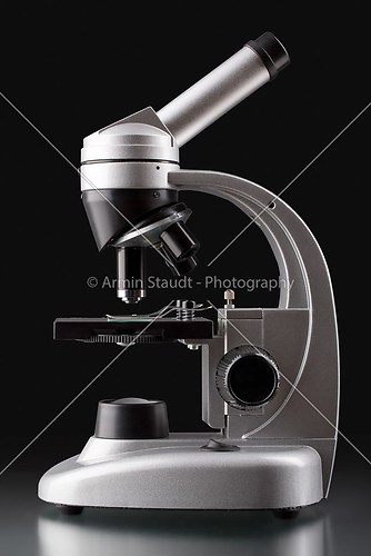 close up of a silver microscope, with black background
