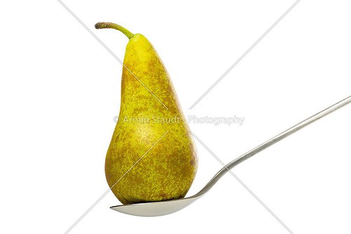 close up of a pear, standing on a spoon, isolated on white