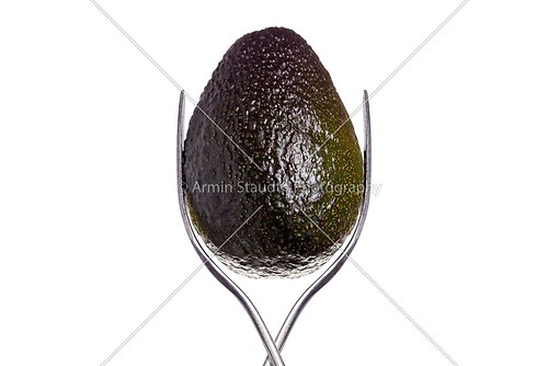 avocado between two forks, isolated on white