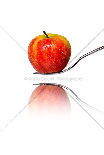 an red apple on a fork with reflection, isolated on white