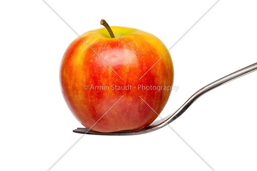 an red apple on a fork, isolated on white