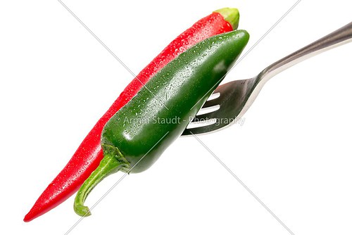 green and red hot chili on a fork, isolated on white