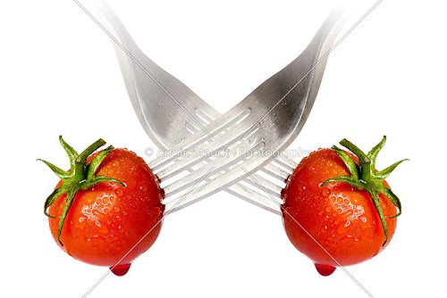 cherry tomato spiked by a fork with reflection, isolated on whit