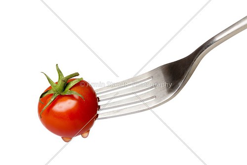cherry tomato spiked by a fork , isolated on white