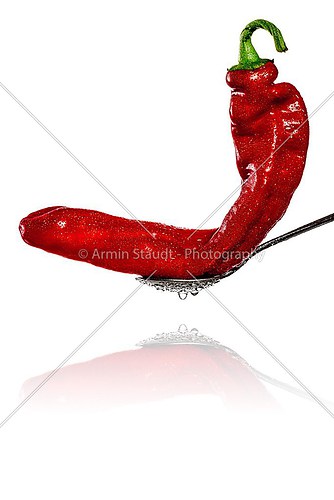 red wet Bell Pepper on a spoon with reflection