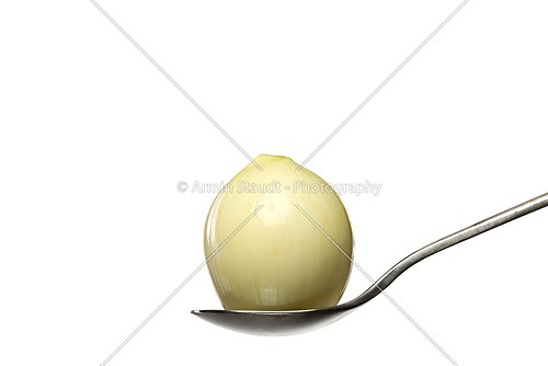 peeled onion on a spoon, isolated on white