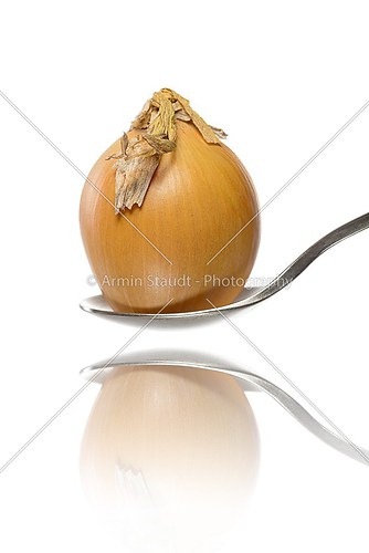 reflected  unpeeled onion on a spoon, isolated on white