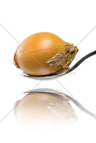 onion laying on a spoon, isolated on white