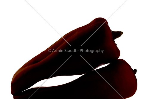 two red paprika in backlight, are laying on each other, isolated