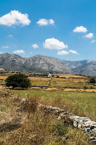 greek landscape with meadow, mountain and blue sky, white chapel