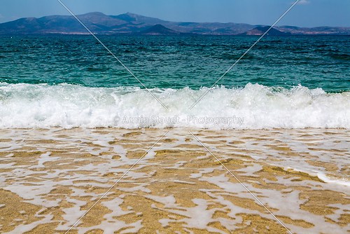 ocean with island in background and froth