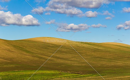 Plowed field with hills and some cloudes