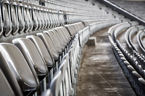 some rows of gray stadium seats, shoot from the side