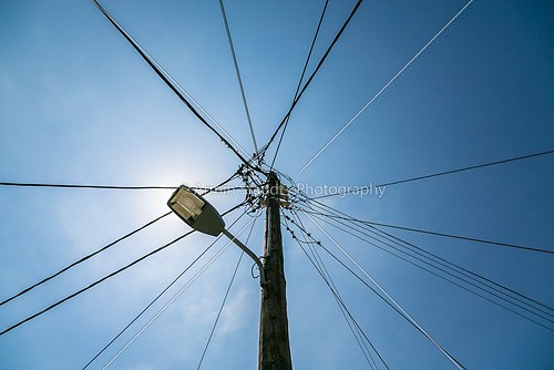 old street light with many cables connected, isolated on blue sk