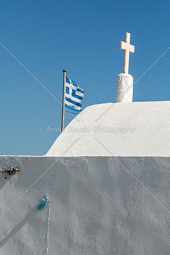 greek flag behind a white chapel, isolated on blue sky