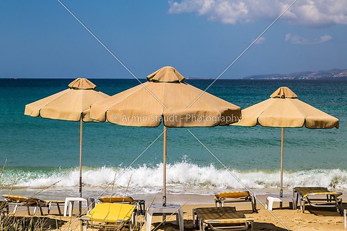 three orange, old  parasols and sunlounger with blue ocean in ba