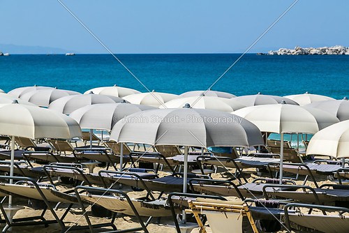 a group of parasols and sun ounger with blue ocean in background