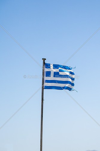 old ragged greek flag, isolated on blue sky