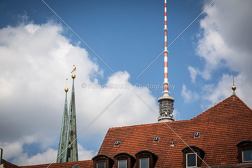 steeple and top of the berlin tv tower behind a red roof
