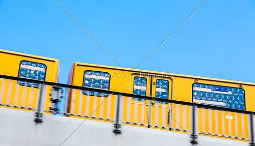 yellow berlin subway moving on a bridge isolated on blue sky