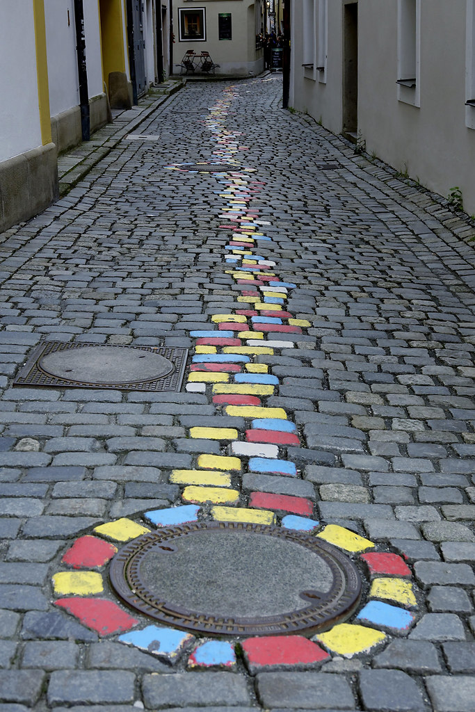 One Way (One Way) | brightly painted cobblestones mark a direction | cobblestones, built structure, outdoors, no people, day, colors, houses, buildings, homes, row of houses, block