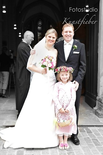 Braut, Bräutigam und Blumenkind vor der Kirche